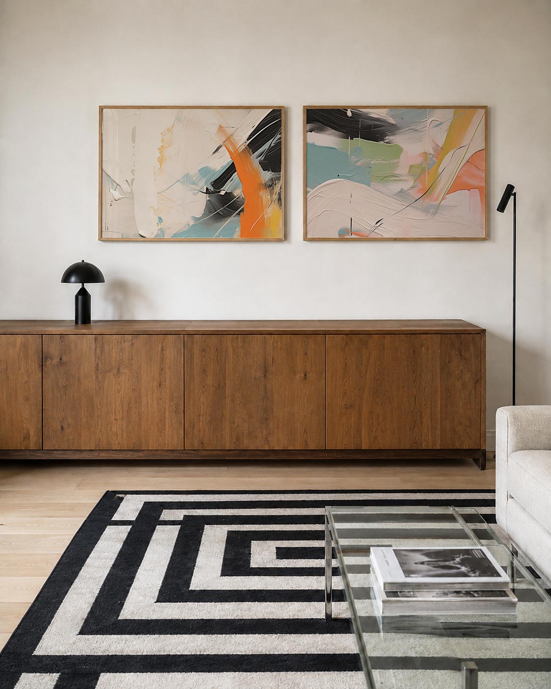 Twee liggende posters met vloeiende witte, oranje en blauwe kleurvlakken, met krachtige zwarte, aan de muur in een interieur