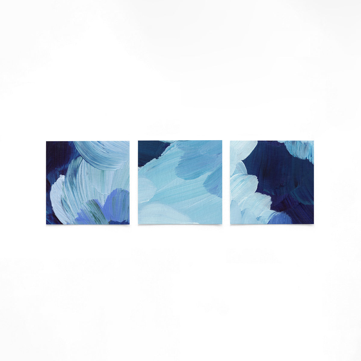 Drie vierkante posters met blauwe abstracte kunst op een gebroken witte achtergrond