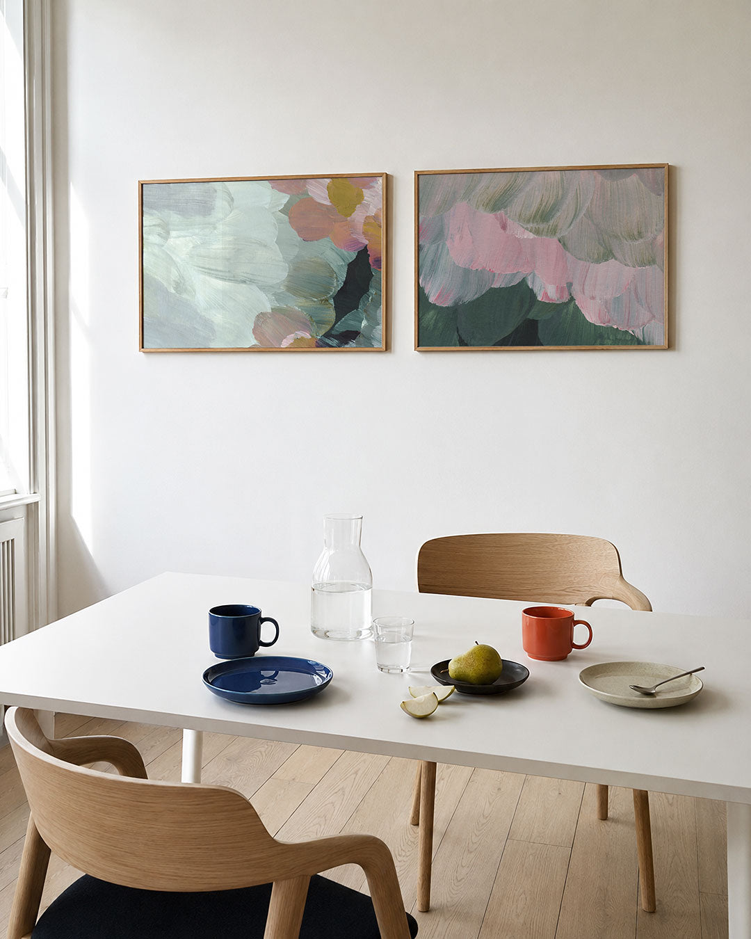 Twee liggende posters met zachte penseelstreken in pastelkleuren, aan de muur in een interieur