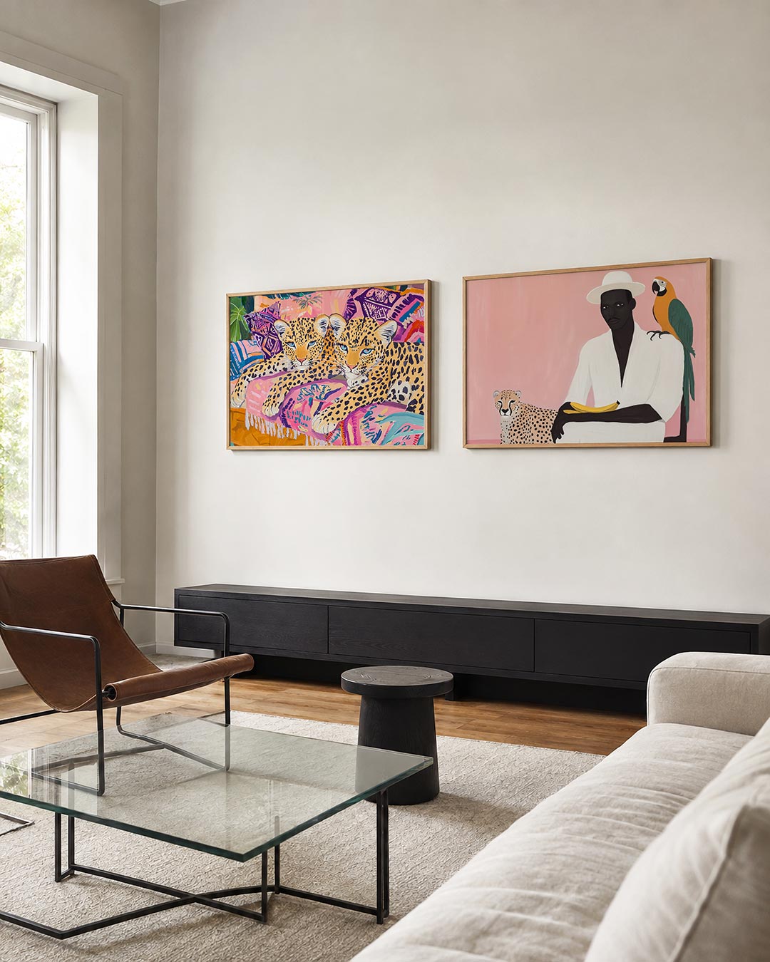 Twee liggende posters met twee luipaarden op kussens met roze, paarse en blauwe patronen, aan de muur in een interieur