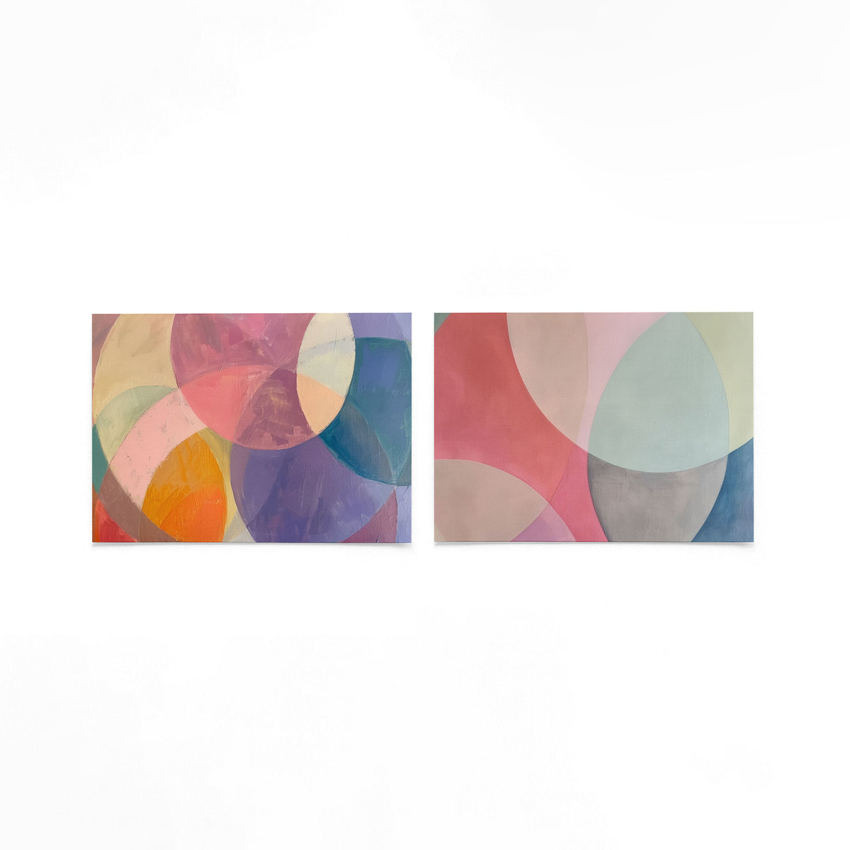 Twee liggende posters met overlappende cirkels in zachte tinten roze, paars, geel en blauw op een gebroken witte achtergrond