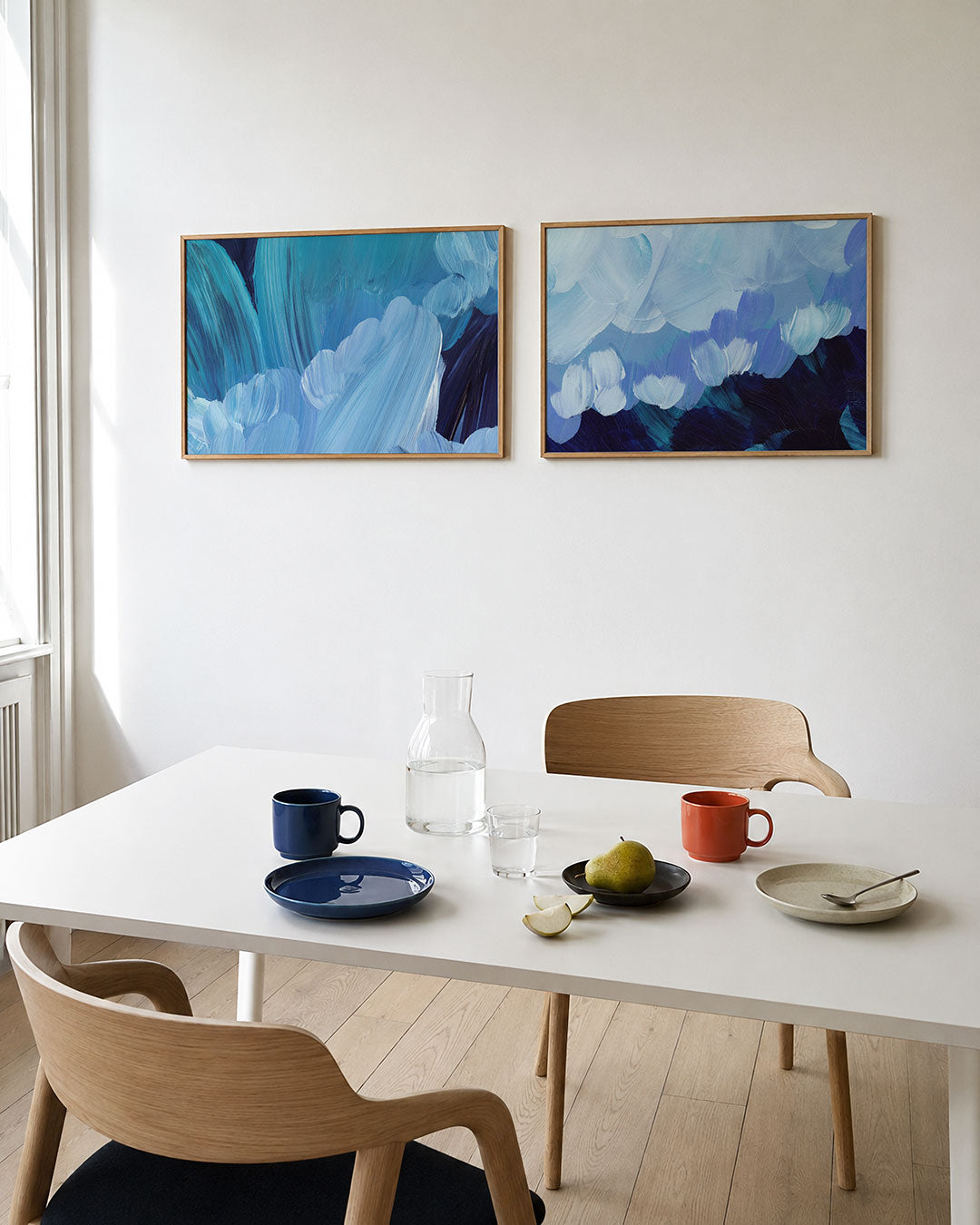Tweedelige posterset met vloeiende blauwe penseelstreken die elkaar overlappen, getoond in een interieur