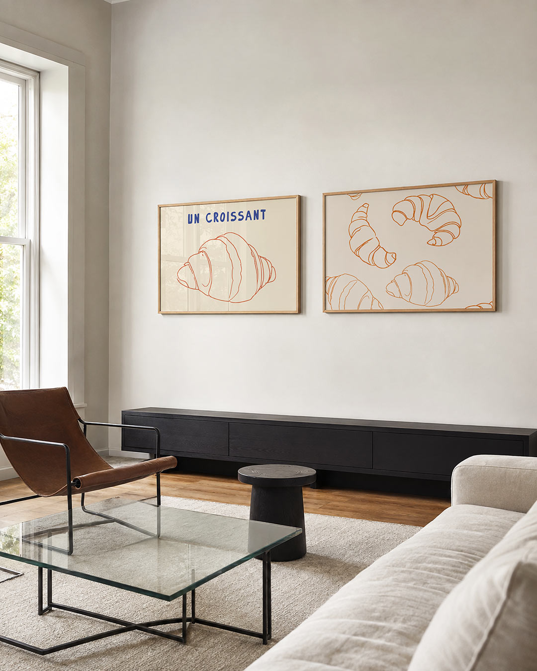 Tweedelige posterset met een oranje lijntekening van een croissant en de blauwe tekst ‘UN, getoond in een interieur