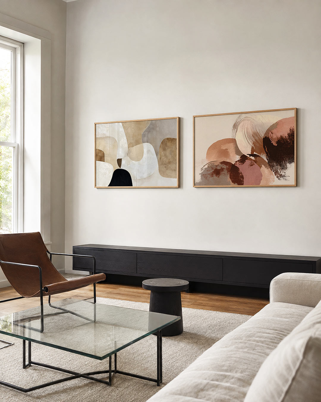Twee liggende posters met zachte, organische vormen in beige, wit en zwart, aan de muur in een interieur