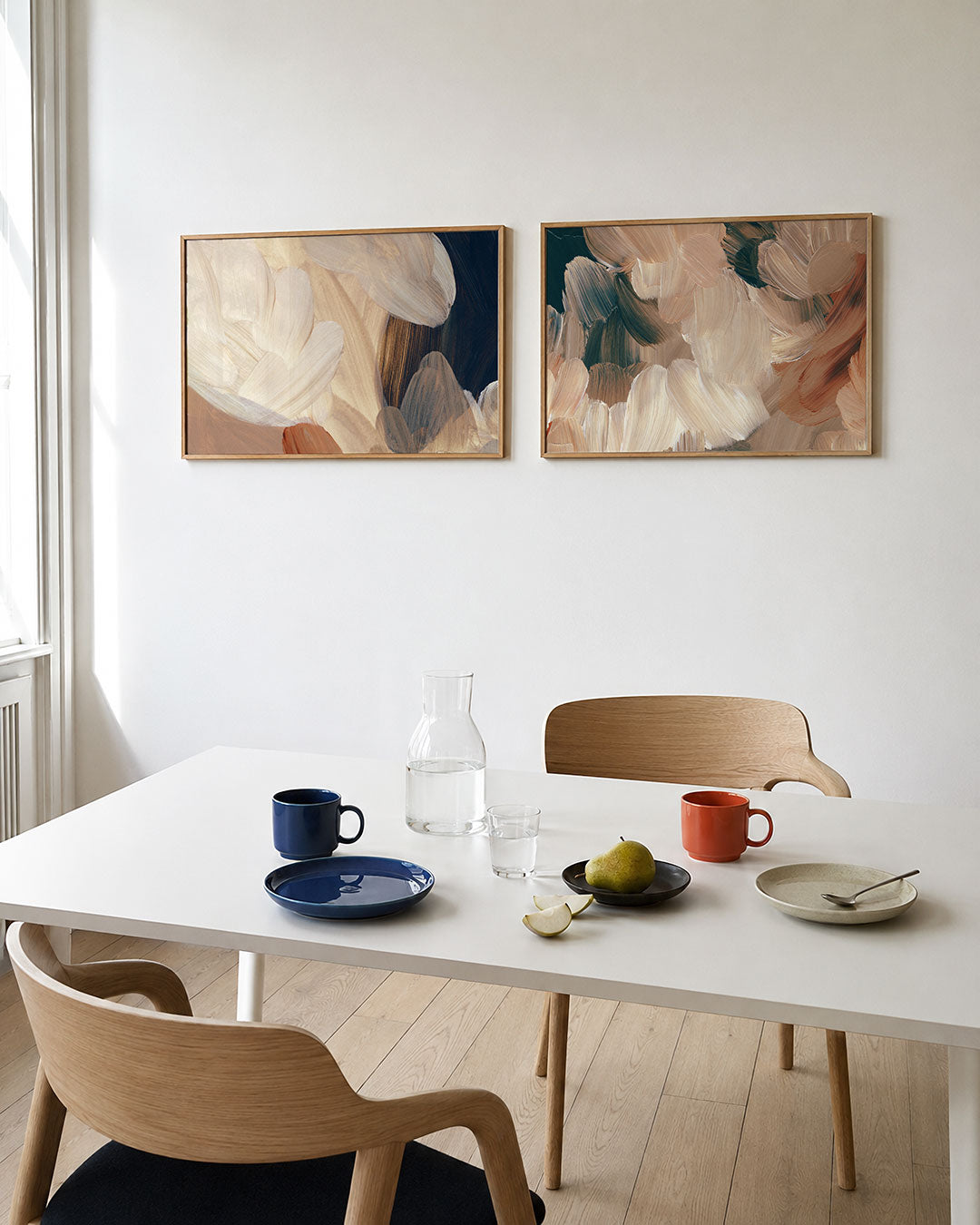 Twee liggende posters met zachte penseelstreken in warme tinten, aan de muur in een interieur